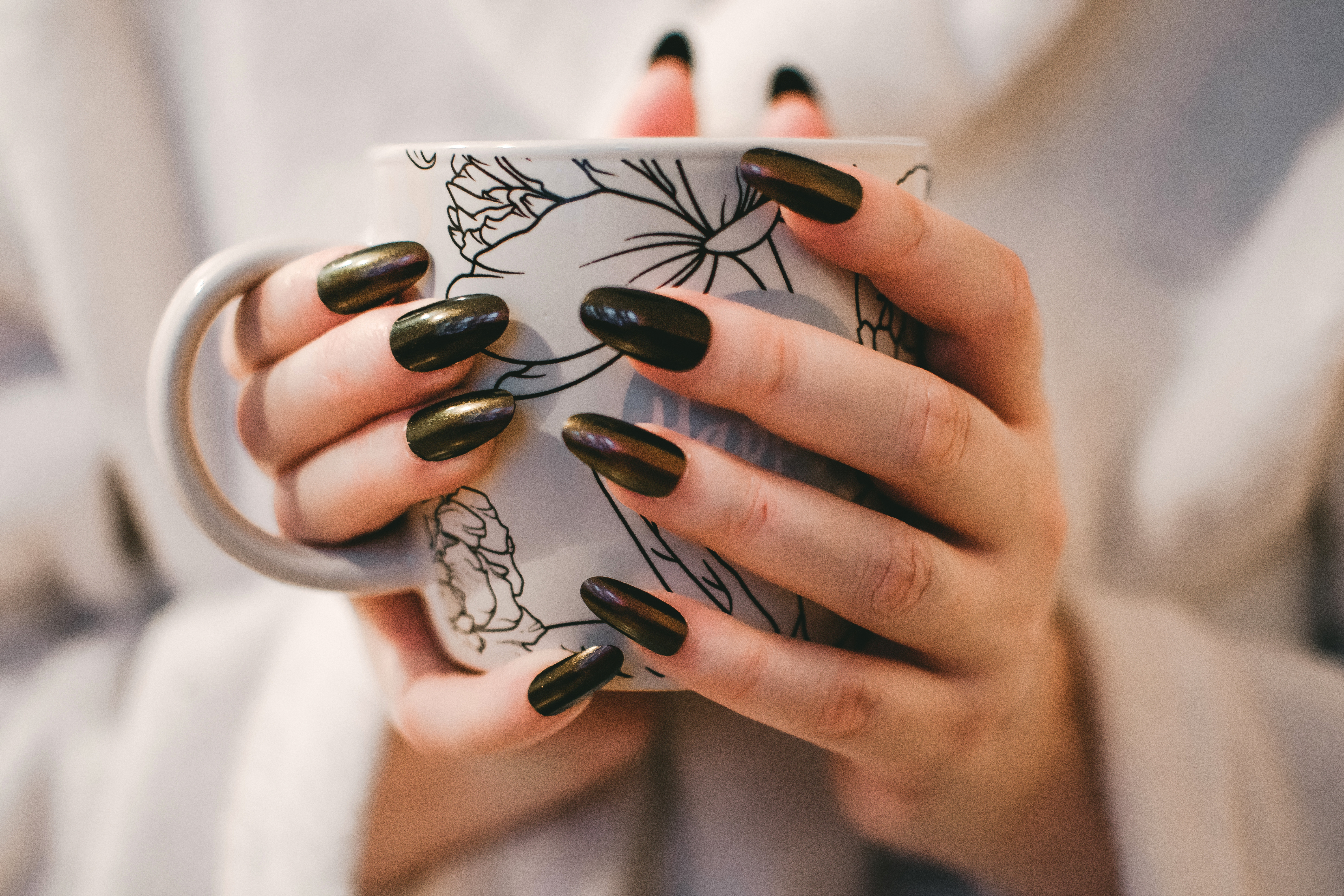 Canva - Woman With Black Manicure Holding White and Grey Floral Ceramic Cup