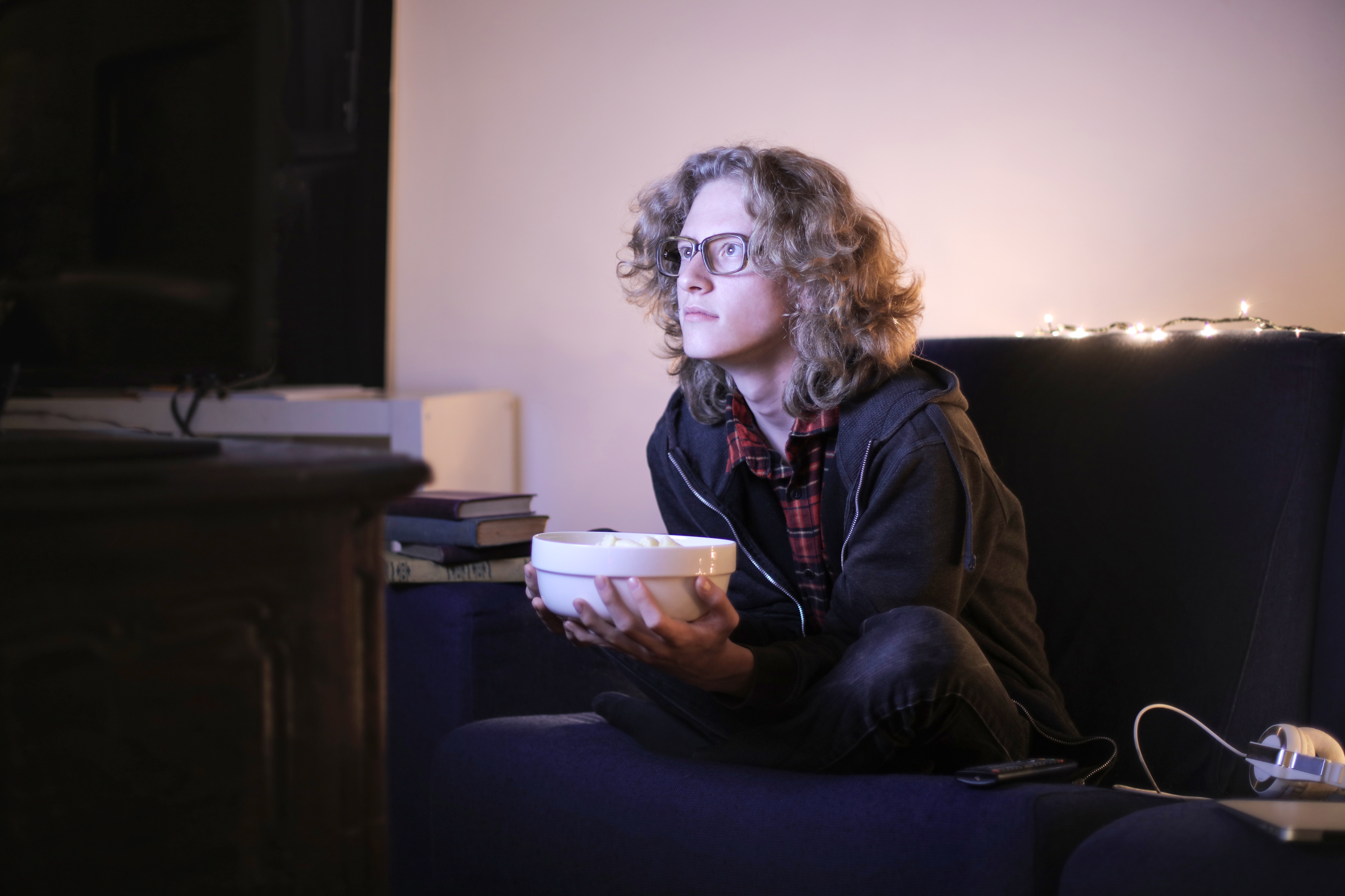 Canva - Focused man with bowl of popcorn watching TV at home