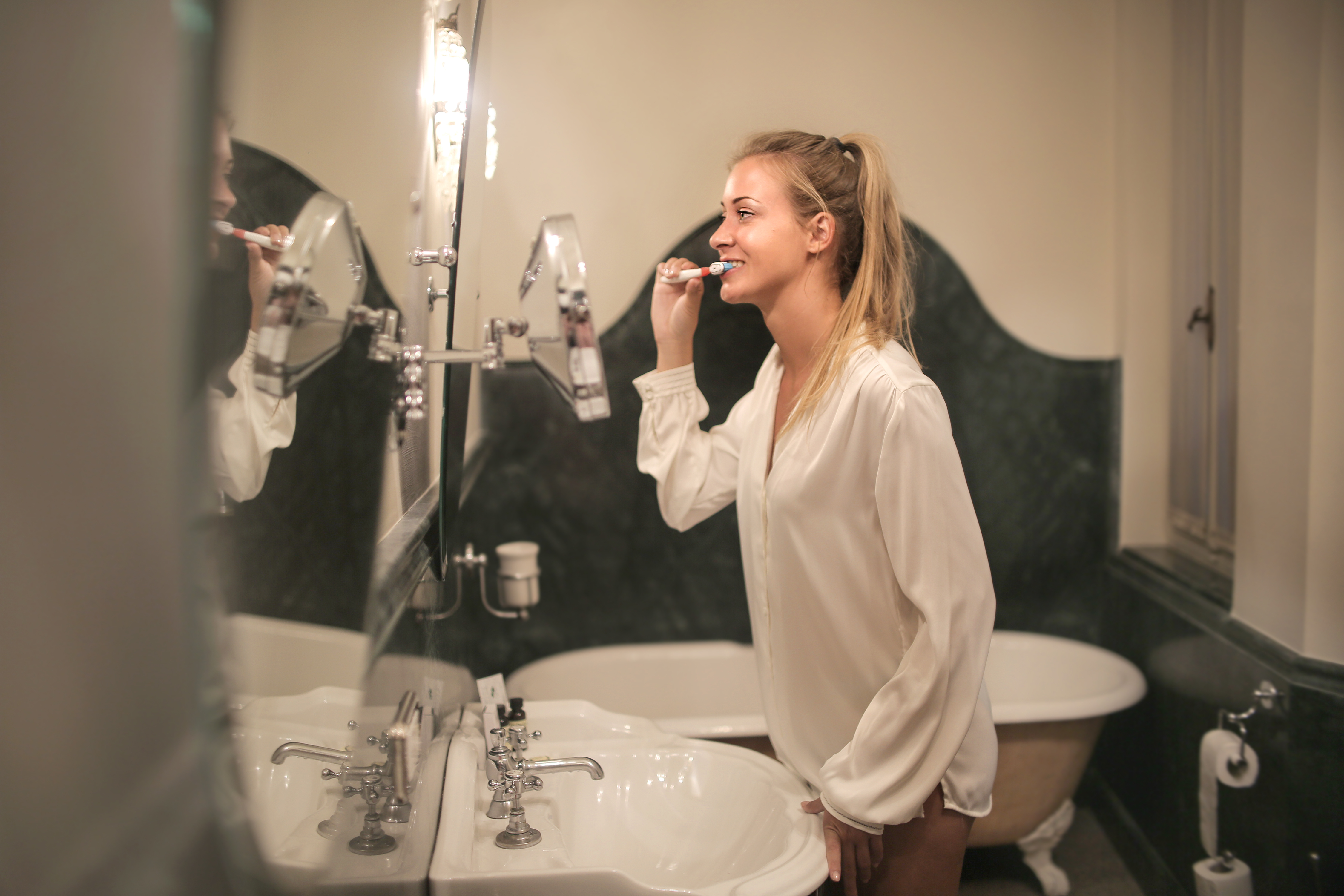 Canva - Young woman cleaning teeth in bathroom